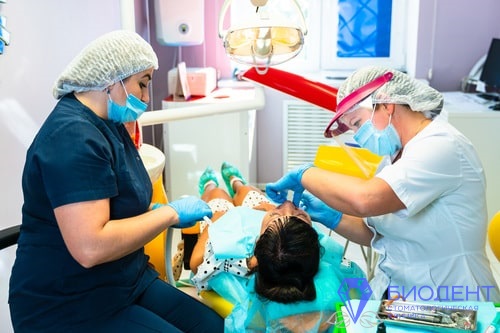 Стоматолог лечит зубы женщине
