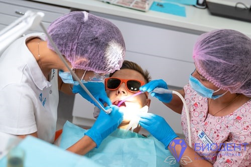 Стоматолог лечит зубы подростку