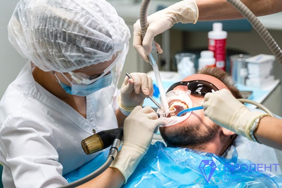 Стоматолог клиники Биодент проводит чистку зубов