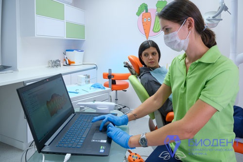 Врач-ортодонт за ноутбуком смотрит 3D-модель зубов