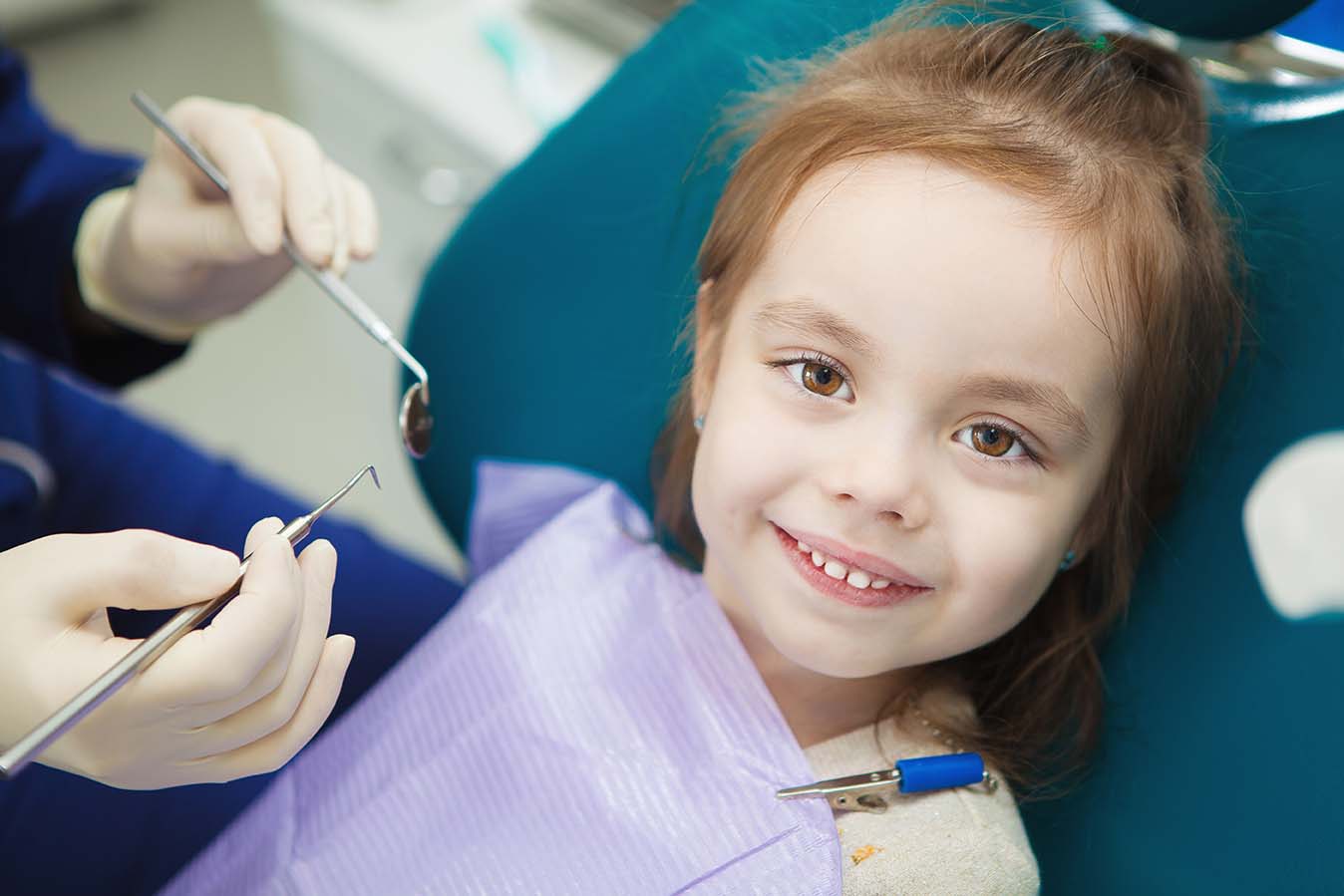 Детский стоматолог лечит молочные зубы ребенку