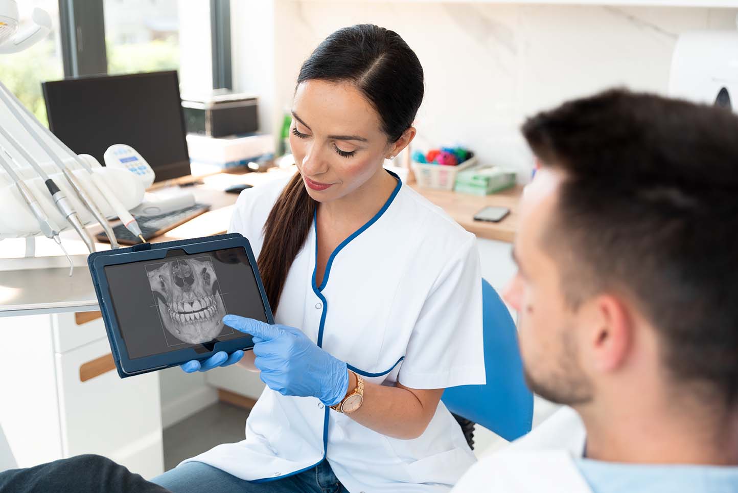 Врач показывает пациенту 3D-снимок челюсти сделанный с помощью КТ зубов
