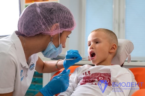 Врач-стоматолог осматривает зубы ребенка